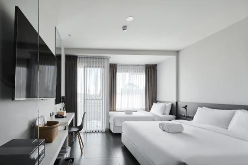a white hotel room with two beds and a television at POR Arak in Chiang Mai