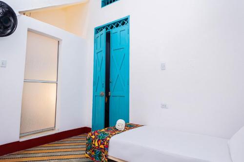 a blue door in a white room with a bed at Hotel Kasa Dokari in Honda