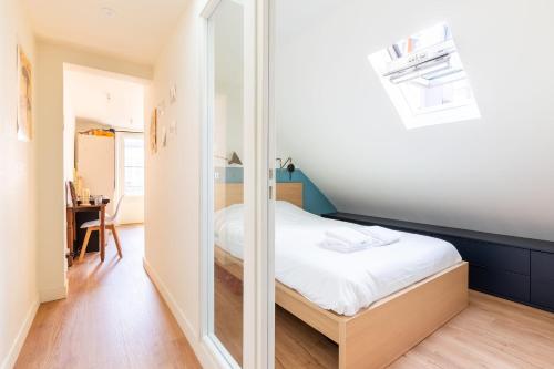 une petite chambre avec un lit et un miroir dans l'établissement Harmonie sous Elegance au Marais, à Paris