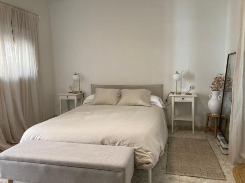 a white bedroom with a large bed and two tables at La Santa in Almagro