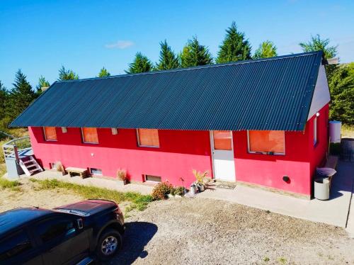 a red building with a black roof at Tres Piquillines in Puerto Madryn