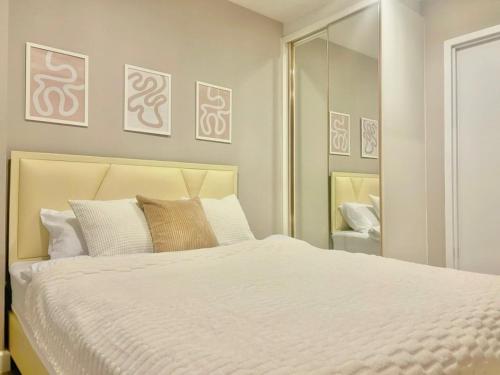 a bedroom with a white bed and a mirror at Metro luxe riverfront resort style condo in Ban Sai Ma
