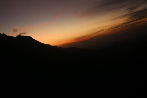 a sunset over a mountain with the sky at Jungle Cave in Ella
