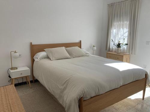 a bedroom with a large bed with white sheets and a window at La Santa in Almagro