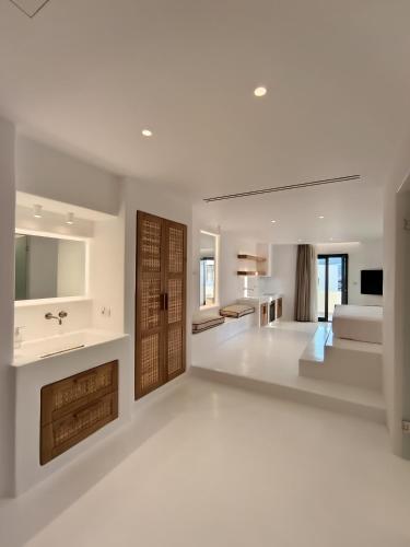 a white living room with a bed and a sink at Yialos Ios Hotel in Ios Chora