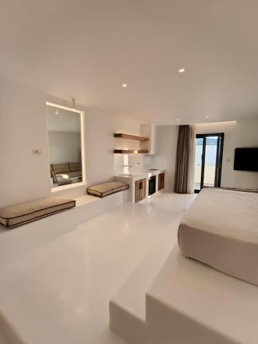 a white bedroom with a bed and a large mirror at Yialos Ios Hotel in Ios Chora