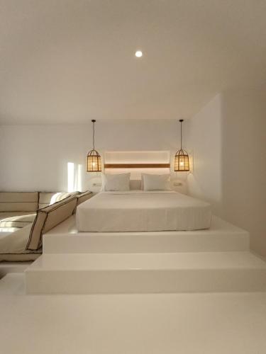 two beds in a white room with two lights at Yialos Ios Hotel in Ios Chora