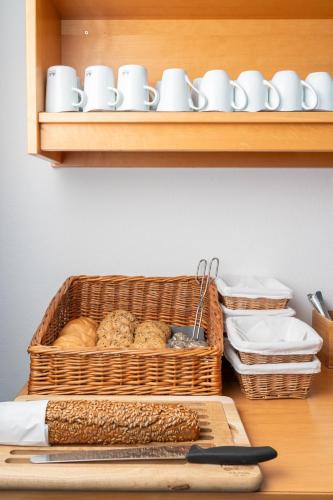 a basket of bread and cups on a shelf at Hotel Laaxerhof in Obertauern