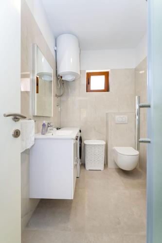 a white bathroom with a sink and a toilet at Holiday home Lorena in Novigrad Dalmatia