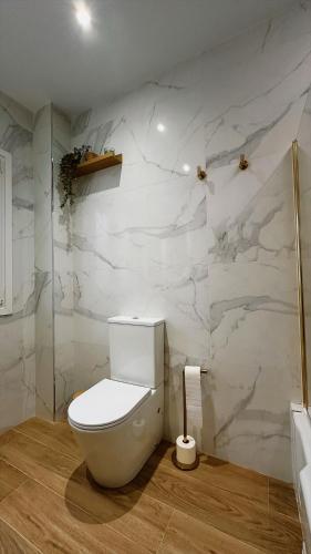 a bathroom with a white toilet and a marble wall at La Casa del Escudo in Trujillo