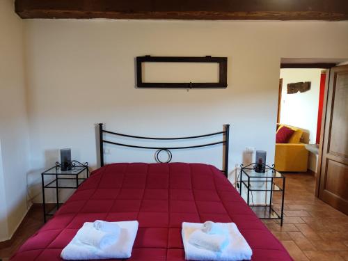 a bedroom with a red bed with two white towels at Casa del Contadino in Sansepolcro