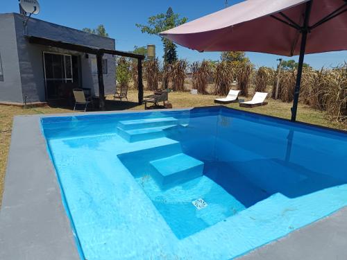パイサンドゥーにあるRetiro San Francisco 2 hasta 6 huespedes -Pais Uruguayの青いスイミングプール(階段付)と傘
