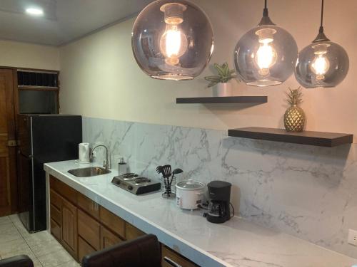 a kitchen with a sink and two pendant lights at Hospedaje Ana Lu 1 Only 10 minutes from airport in Alajuela