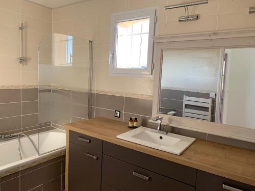 une salle de bain avec un lavabo, une baignoire et un miroir dans l'établissement Cetanou villa 4 étoiles piscine et climatisation au calme, à La Londe-les-Maures