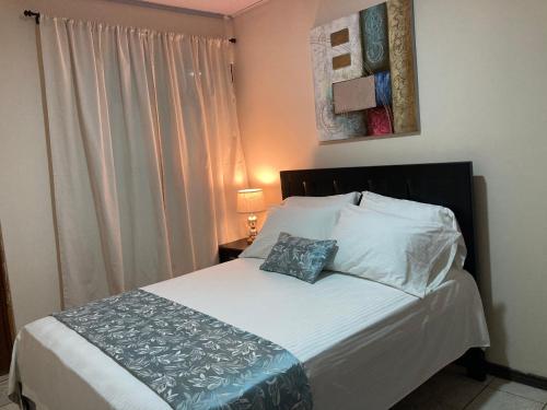 a bedroom with a bed with a pillow and a window at Hospedaje Ana Lu 1 Only 10 minutes from airport in Alajuela