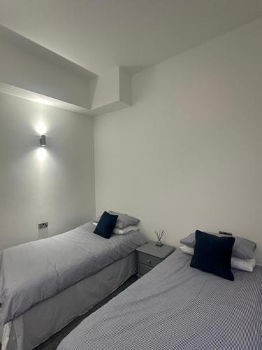 two beds in a room with white walls and blue pillows at Medstead Lodge in Four Marks