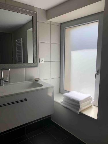 La salle de bains est pourvue d'un lavabo, d'une fenêtre et de serviettes. dans l'établissement Maison de pêcheur à 1,5km de la mer, à Blainville-sur-Mer