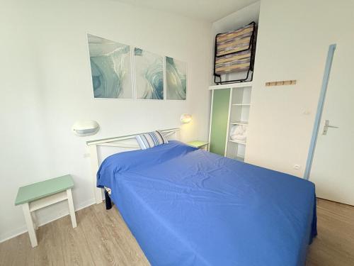 a bedroom with a blue bed and a table at La Cascada in Dolus d'Oléron