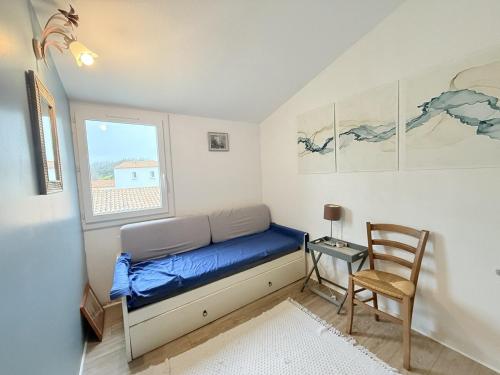 a bedroom with a bed and a chair and a window at La Cascada in Dolus d'Oléron