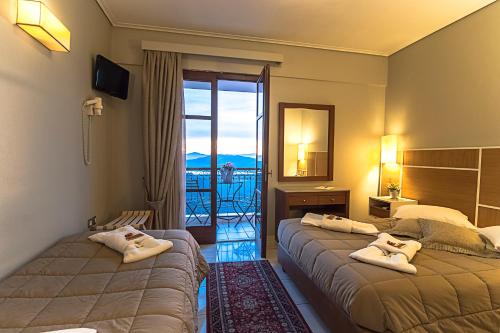 a hotel room with two beds and a balcony at Fedriades Delphi Hotel in Delfoi