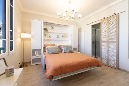 - une chambre avec un lit doté de draps orange et d'oreillers bleus dans l'établissement Le Soleil, à Antibes