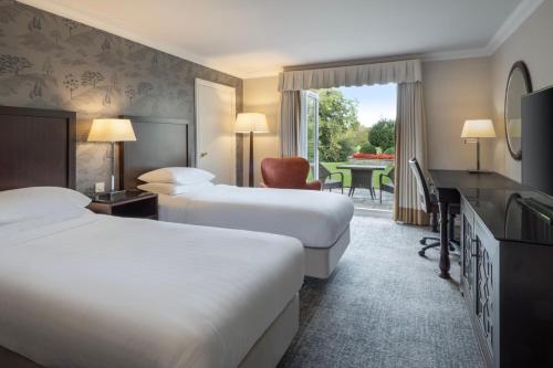 a hotel room with two beds and a desk at Delta Hotels by Marriott St Pierre Country Club in Chepstow