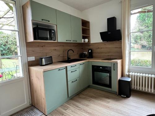 La cuisine est équipée de placards verts, d'un évier et d'un four micro-ondes. dans l'établissement Un secret bien gardé, à Fontenay-le-Fleury