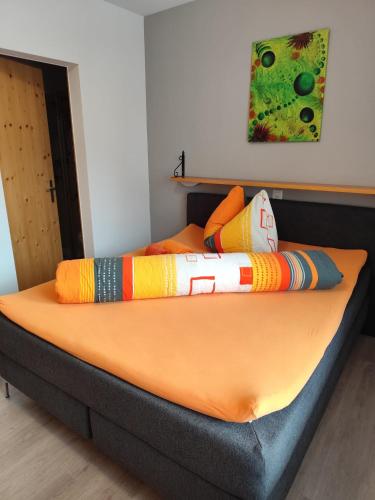 a bed with colorful pillows on top of it at Ristorante Pensione Chalet Stazione in Poschiavo