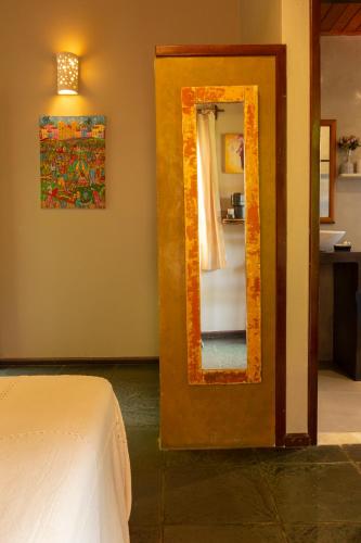 a bedroom with a mirror and a bed in a room at Pousada Aquarela in Morro de São Paulo