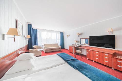 a hotel room with a bed and a flat screen tv at Hotel Lidia Spa & Wellness in Darłówko