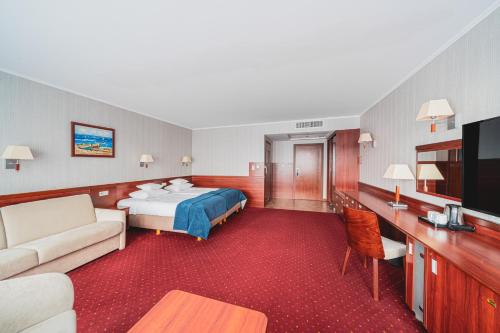 a hotel room with a bed and a tv at Hotel Lidia Spa & Wellness in Darłówko