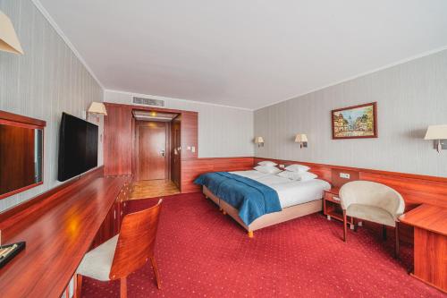 a hotel room with a bed and a flat screen tv at Hotel Lidia Spa & Wellness in Darłówko