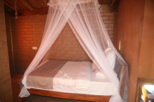 a bed with a mosquito net in a room at Jungle Cave in Ella