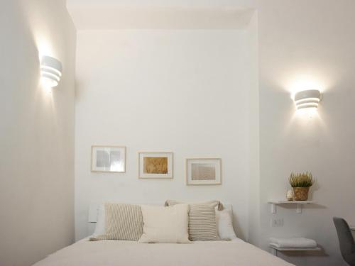 een slaapkamer met witte muren en een bed met kussens bij UniHome Napoli in Napels
