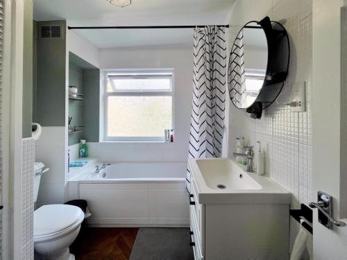 a bathroom with a tub and a sink and a toilet at Cozy sunlit room in west London in Yiewsley