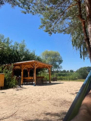 a picnic shelter in a park with a tree at Noclegi nad jeziorem Brdów Agroturystyka pod Wierzbą in Brdów