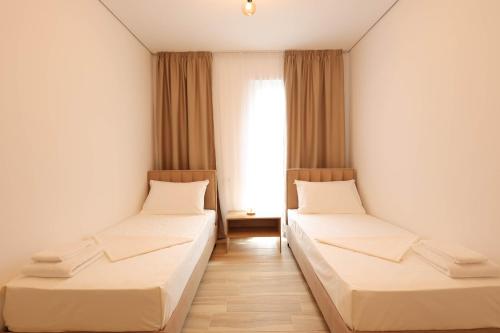 two beds in a room with a window at SanPietro Vacation Apartments in Durrës