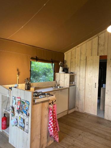 a kitchen with wooden walls and a stove top oven at glamping met landelijk uitzicht in Spanga