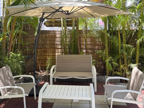a patio with two chairs and an umbrella at Location T2 idéalement située in Bois de Nèfles