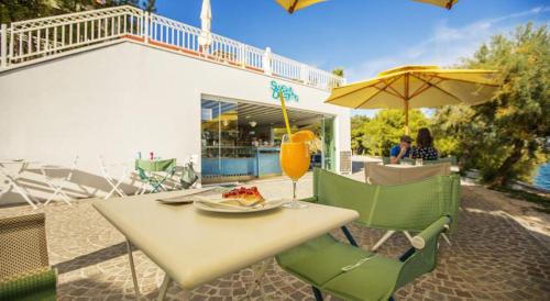 a table with a plate of food and an umbrella at Mobile Homes Danijela in Amadria Park Trogir in Seget Vranjica