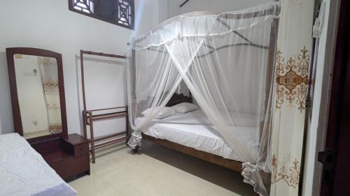 a bedroom with a canopy bed with white sheets at Villa Dewdrops in Hikkaduwa