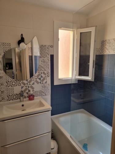 une salle de bain avec un lavabo, une baignoire et un miroir dans l'établissement Le Ti'Bo- Appart T3 proche plage, à Narbonne-Plage