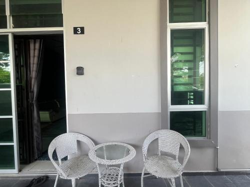 three chairs and a table in front of a building at Homestay Axalea in Muar