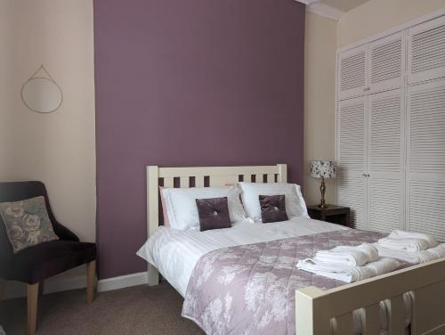 a bedroom with a bed with purple walls and a chair at Castle Brae Apartment in Stirling