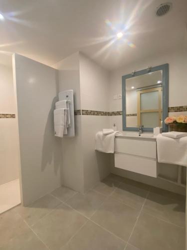 a white bathroom with a sink and a mirror at La petite maison in Solesmes