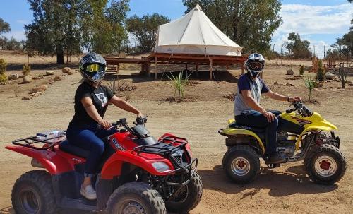 two people riding on atvs in front of a tent at Lago Valle Wine Glamping in Valle de Guadalupe