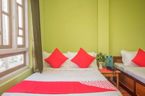 a small room with a bed with red pillows at Hotel O Demadzong in Gangtok