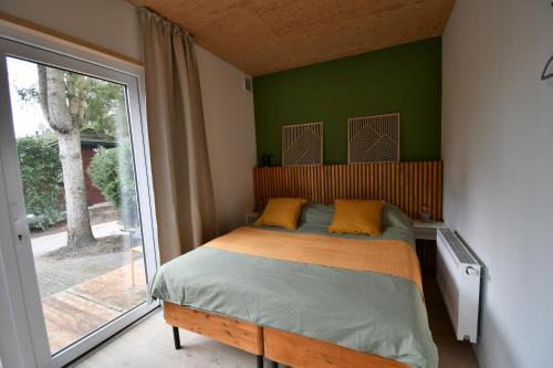 a bedroom with a bed with green walls and a window at Black Cabin Veluwe - Wellness in het bos - Sauna in Putten