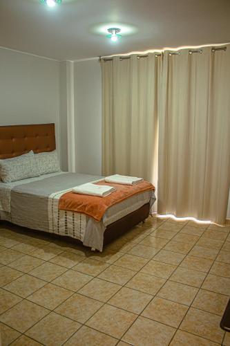 a bedroom with a bed with curtains and a tiled floor at DEL VALLE HOUSE II in Ica
