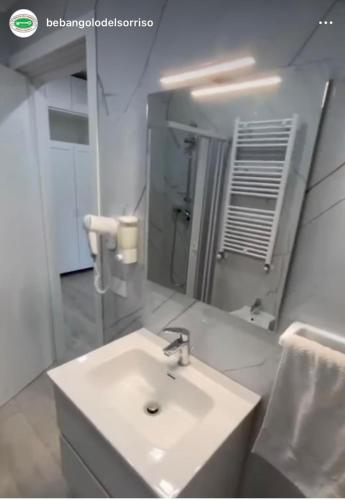 a white bathroom with a sink and a mirror at L'Angolo Del Sorriso in Naples
